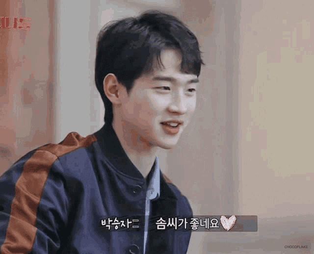 a young man in a blue jacket is smiling with a heart in the corner