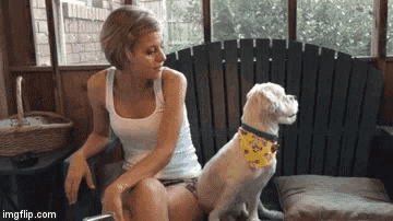 a woman sits on a couch with a dog wearing a bandana