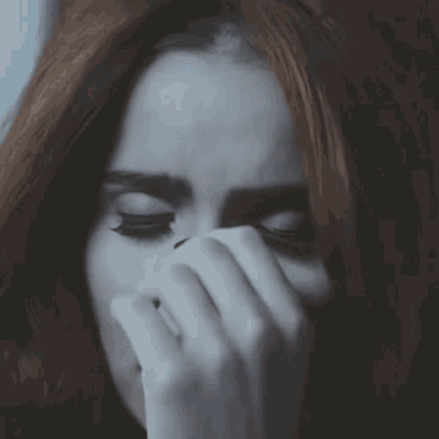 a woman with long red hair is covering her face with her hand
