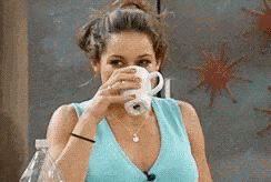 a woman in a blue shirt is drinking from a white cup