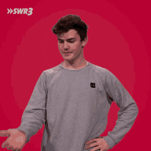 a man wearing a grey under armour sweatshirt is pointing to the right