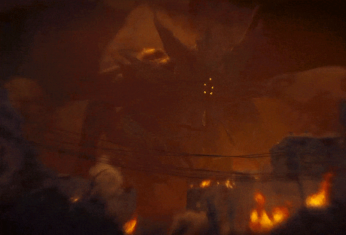 a large monster is surrounded by flames and a crowd of people