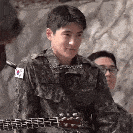 a man in a military uniform is holding a guitar .