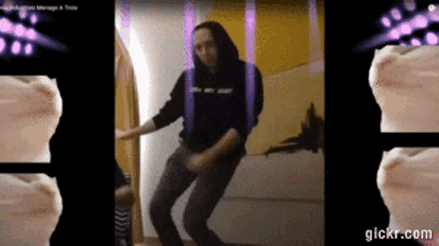 a man in a black hoodie is dancing in a room