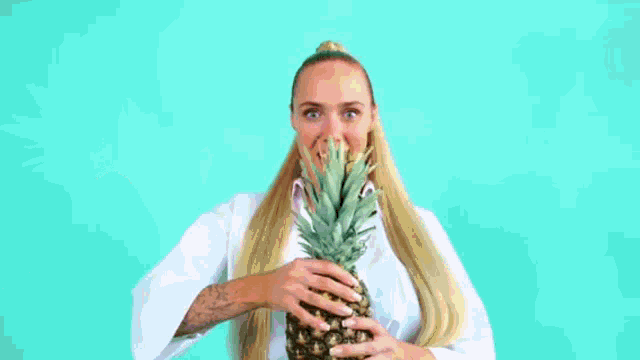 a woman is holding a pineapple in front of her face while confetti is falling on her .