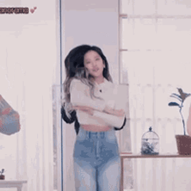 a woman in a white crop top and blue jeans is standing in front of a mirror