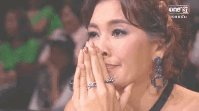 a woman is covering her face with her hands while watching a show on a television .