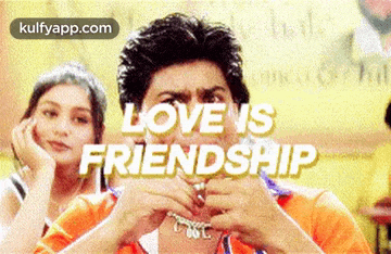 a man is making a heart shape with his hands and the words love is friendship are behind him