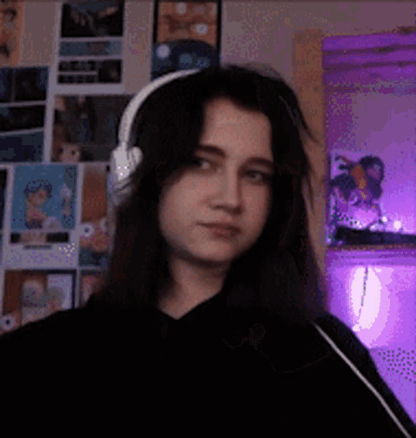a girl wearing headphones is standing in front of a wall of pictures .