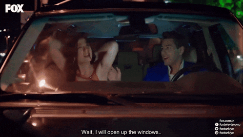 a man and woman are sitting in a car with fox written on the bottom
