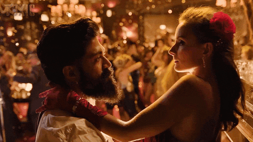 a man with a beard and a woman with a flower in her hair are dancing together
