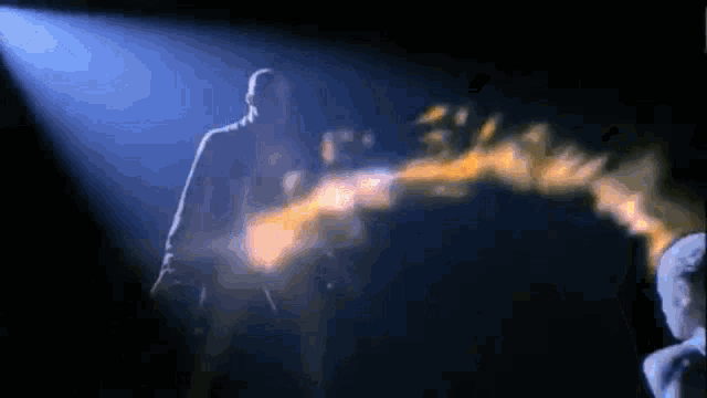 a man is standing in a dark room with a beam of light coming out of his chest