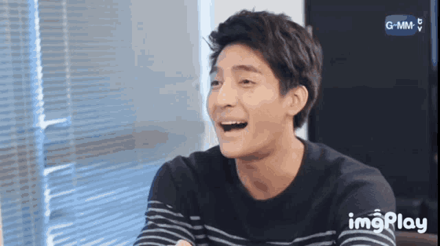 a man in a striped shirt is laughing in front of a screen that says imgplay on it