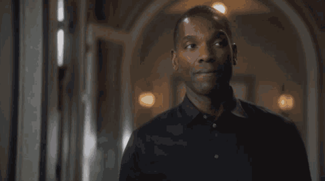 a man in a black shirt stands in a hallway