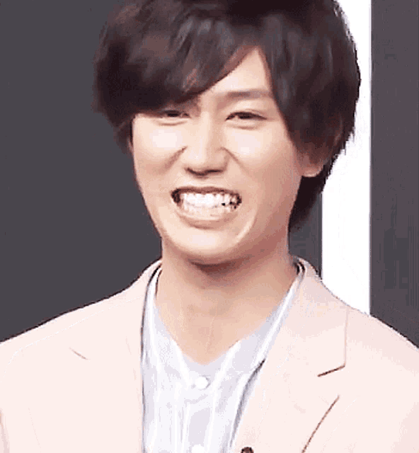 a young man in a pink jacket is smiling