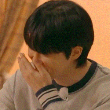 a close up of a person covering their mouth with their hands .