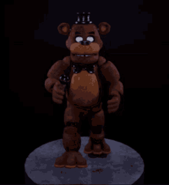 a brown teddy bear with a crown on his head is standing on a pedestal
