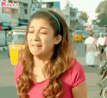 a woman in a pink shirt is standing on a street with her eyes closed .