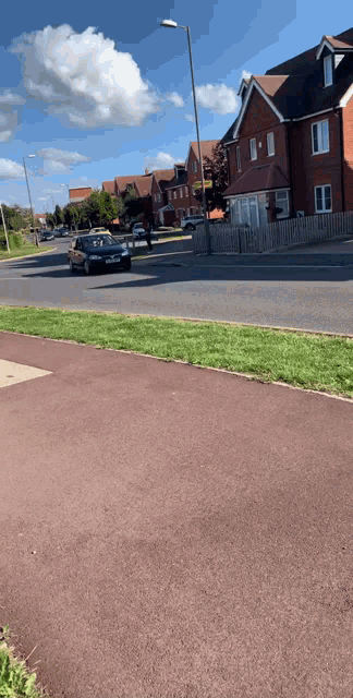 a black car is driving down a street in front of a row of brick houses