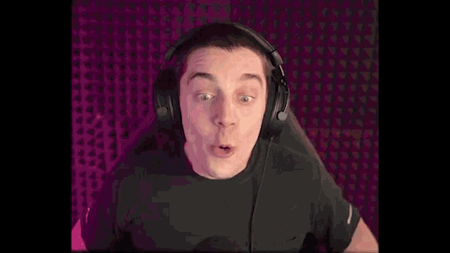 a young man wearing a black shirt and a watch is making a surprised face