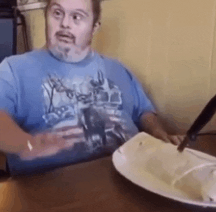 a man with down syndrome is sitting at a table eating food .