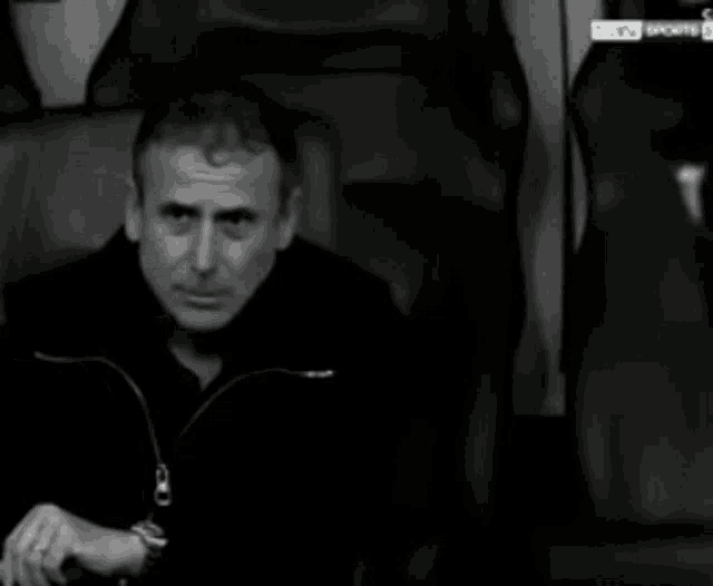 a black and white photo of a man sitting in a chair with bein sports written on the bottom