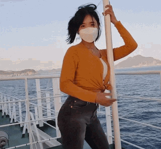 a woman wearing a mask is standing on a boat in the water