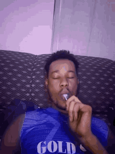 a man is laying on a couch smoking a cigarette .