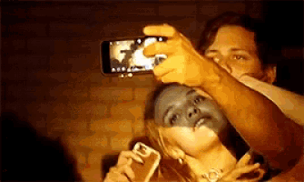a man taking a picture of a woman with his phone