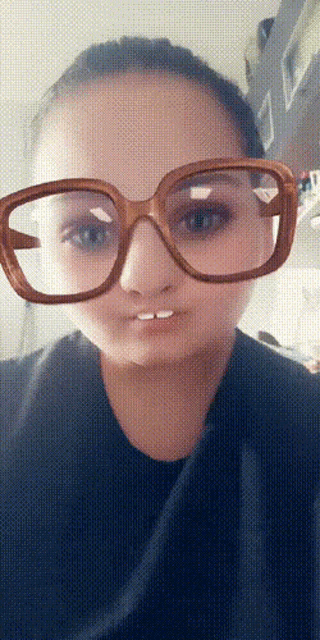 a woman wearing glasses with a wooden frame makes a funny face