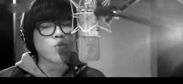 a man wearing glasses and headphones singing into a microphone