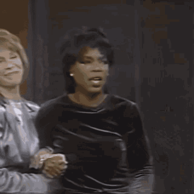 two women are sitting next to each other on a stage and one is screaming .