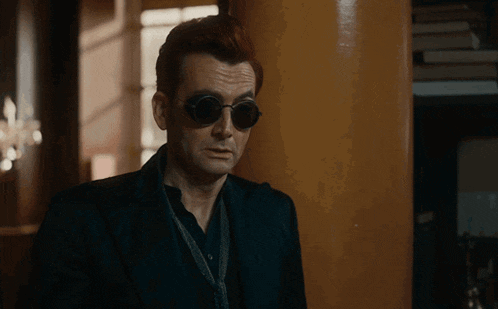 a man wearing sunglasses is leaning against a pillar