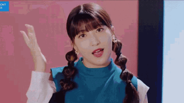 a girl with pigtails is wearing a blue sweater and white shirt