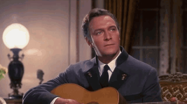 a man in a suit is playing a guitar in a room