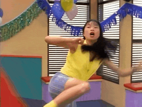 a woman in a yellow tank top is jumping in the air