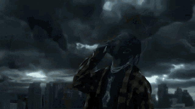 a man with dreadlocks is standing in front of a stormy sky .