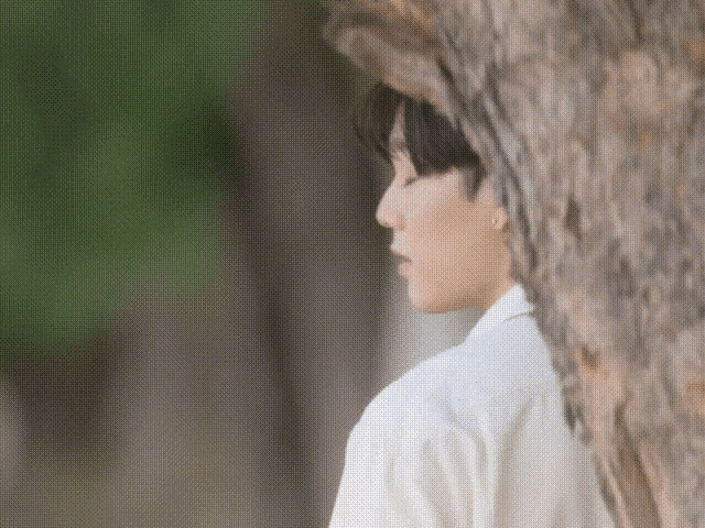 a man in a white shirt is standing next to a tree