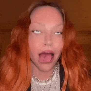 a woman with red hair is making a funny face with her tongue sticking out .