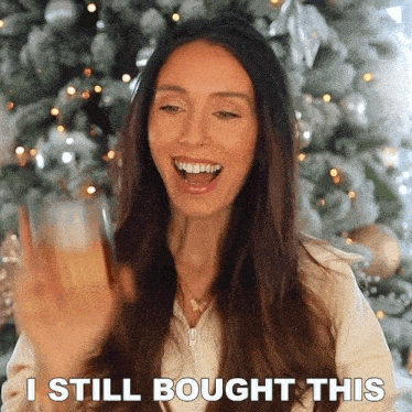 a woman is standing in front of a christmas tree and says i still bought this