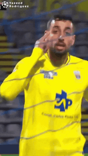 a soccer player wearing a yellow shirt with a blue eap logo on it