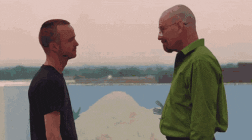 a man in a green shirt stands next to a man in a black shirt