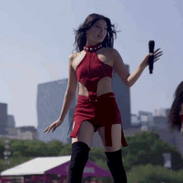 a woman in a red dress is holding a microphone in her hand