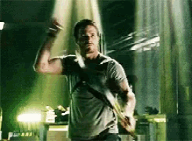 a man in a grey shirt is holding a sword in his hand .