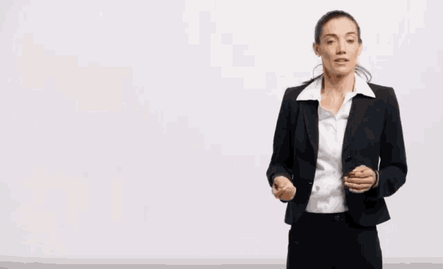 a woman in a business suit stands in front of a sign that says shit hot that 's great