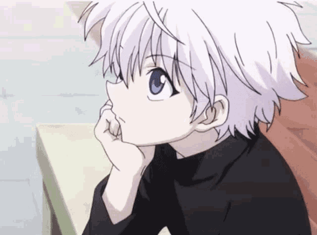 a young boy with white hair and blue eyes is sitting at a table with his hand on his face .