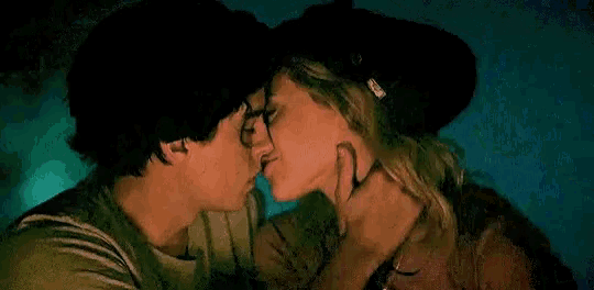 a man and woman are kissing in a dark room .