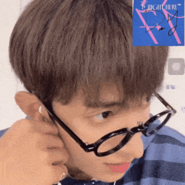 a close up of a person wearing glasses next to a blue sign that says is right here
