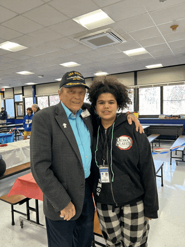 a man wearing a navy hat stands next to a young boy wearing a demon slayer sweatshirt