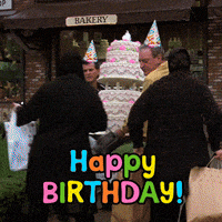 a group of people standing in front of a bakery holding a cake and a sign that says happy birthday